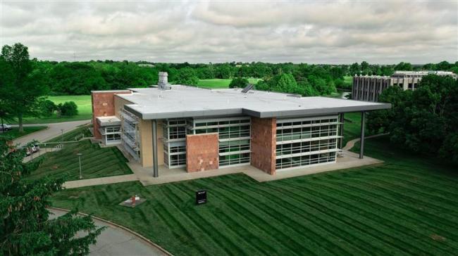 Overhead drone shot of CAER Lab 2: a large, low-slung building made of bricks with windows that almost take up the entire side